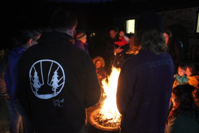 Families sitting and standing around a campfire