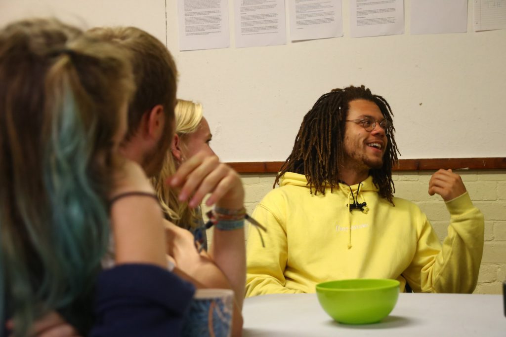 young man in a yellow hoody talking at a meeting