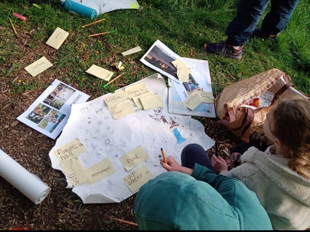 Children doing an activity in a field with flip chart, post it notes and pens