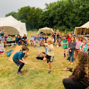 A group of children jump over a stick held by other children