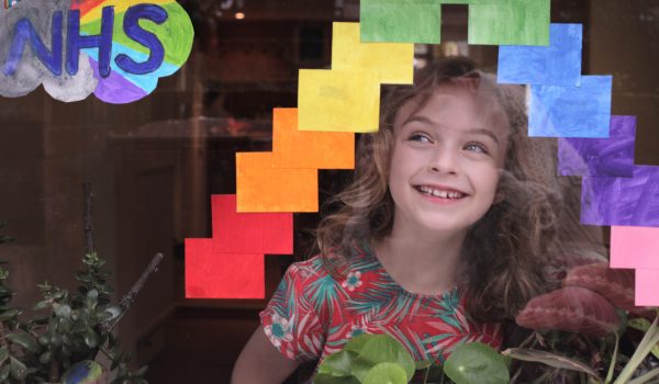 Child smiling through a window with rainbows - dream big at home image