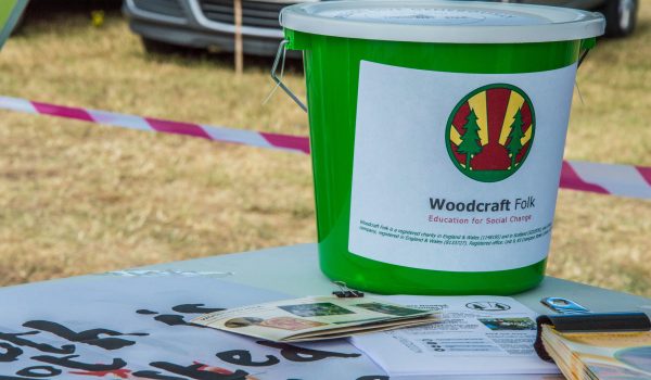 Green fundraising bucket with woodcraft folk logo