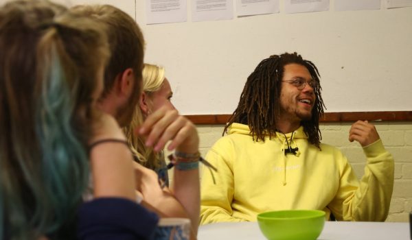 young man in a yellow hoody talking at a meeting