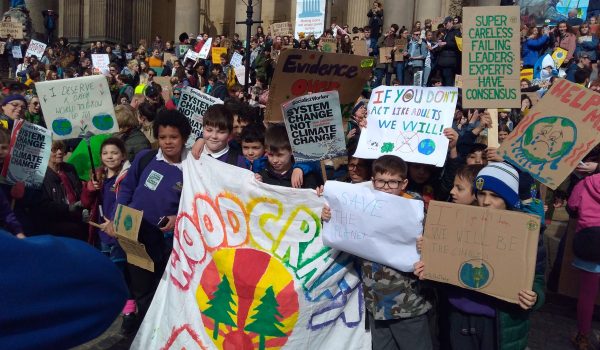 Large group of children with a homepainted woodcraft folk banner at a climate demonstration