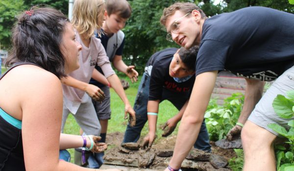 group of volunteers and children building a wall